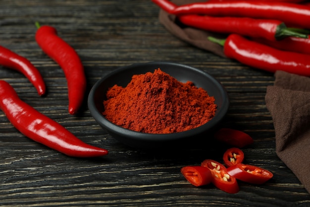 Red chili peppers and powder on rustic wooden