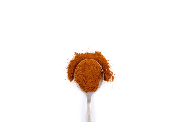 Red chili powder in metal spoon on white 