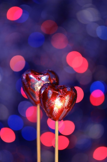 Photo red chocolate hearts wrapped in red foil for valentine's day stack of chocolate heart