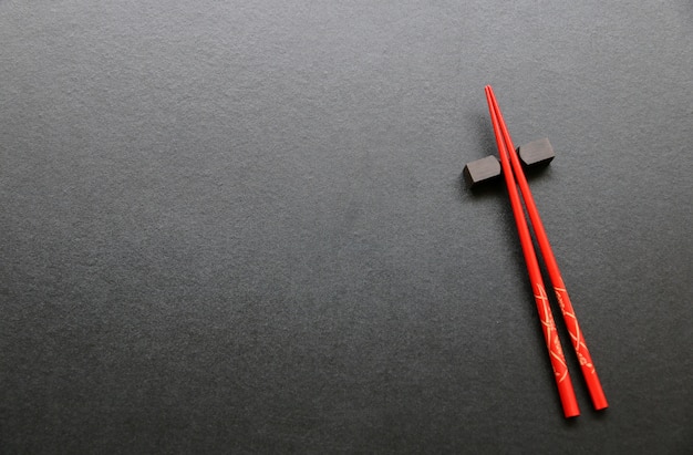 Red chopsticks on black table background Top view