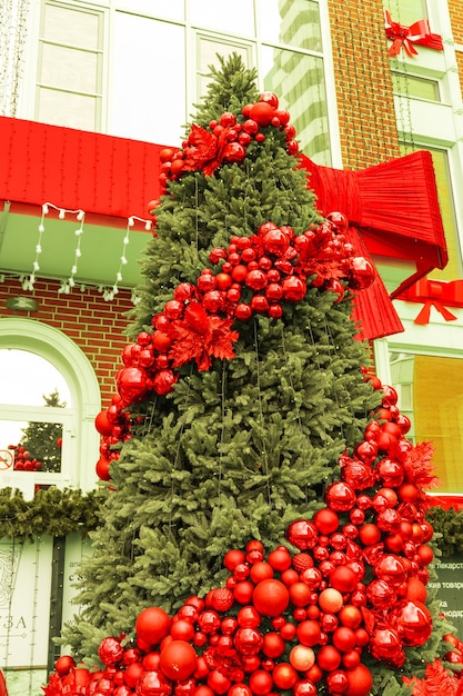 Red Christmas ball on a Christmas tree with a garland on the background of a wooden wall