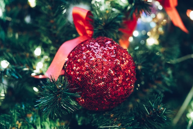 Red christmas ball with sparkles on a christmas tree closeup