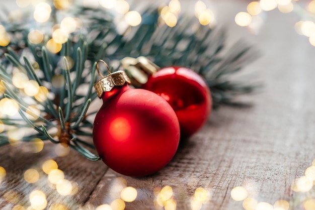 Red christmas balls on wooden background with christmas lights bokeh