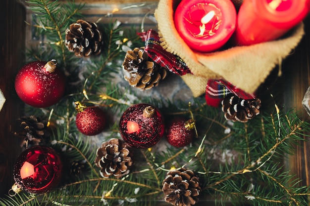 Red christmas decorations on the table at blurred christmas tree with candles . High quality photo