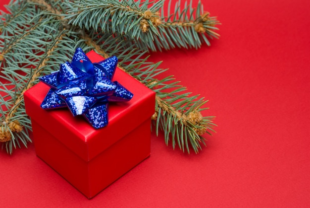 Red Christmas gift box with colored ribbon and Christmas balls on a red background