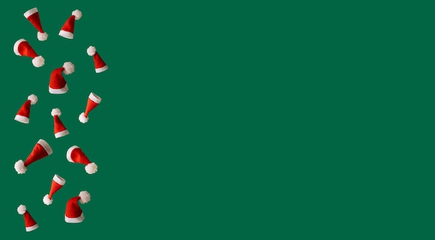 Red Christmas hats on a green background, creative concept of Christmas with free space for text