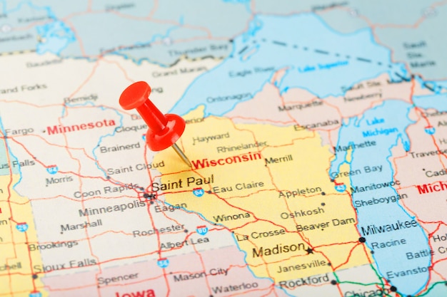 Photo red clerical needle on a map of usa, wisconsin and the capital madison. close up map of wisconsin with red tack