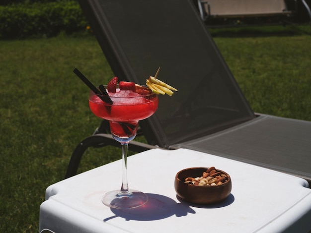 A red cocktail and nuts on the table