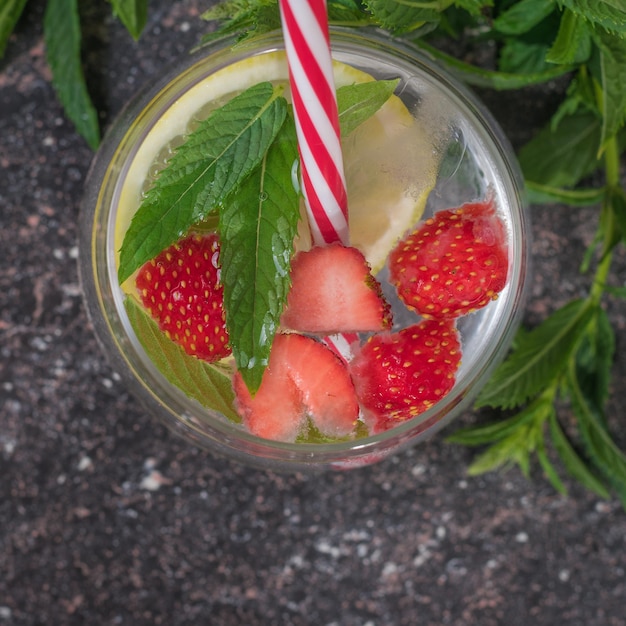 Red cocktail tube in a mug with water lemon and berries