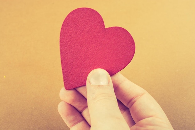 Red color heart shaped object in hand