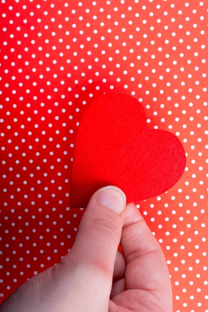 Red color heart shaped object in hand