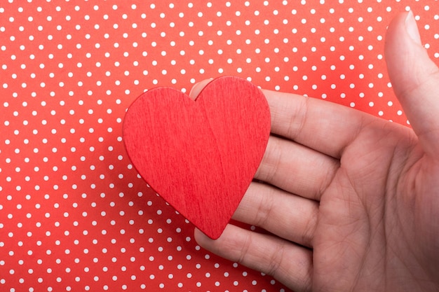 Red color heart shaped object in hand