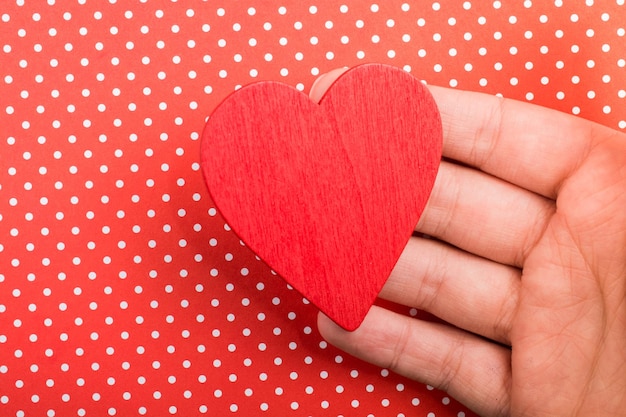 Red color heart shaped object in hand