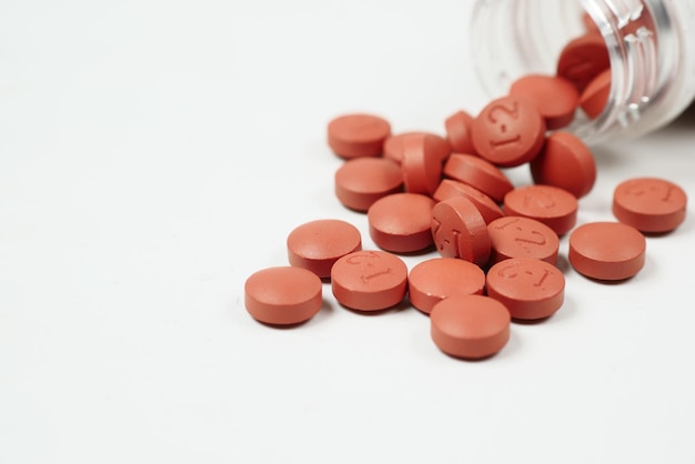 Red color pain killer spilling form a container on white background