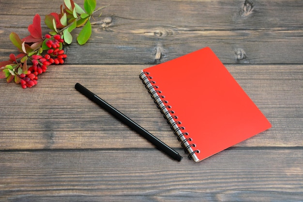 red copybook with black pen on wooden background isolated, close-up