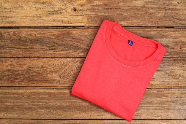 Red cotton T-shirt put on wooden background.