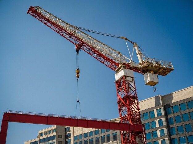 Photo a red crane with a man on it and a building in the background