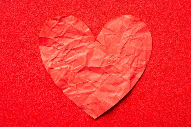 Red crumpled paper heart close up Love devotion relationships concept