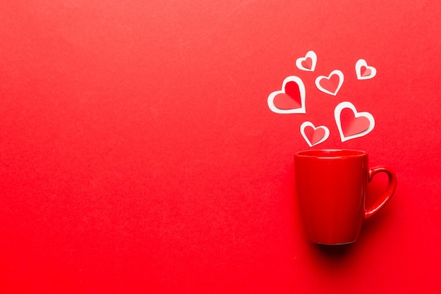 Red cup on colored background splashes of red little hearts top view with copy space