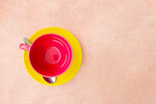 Red cup on yellow plate on pink tablecloth