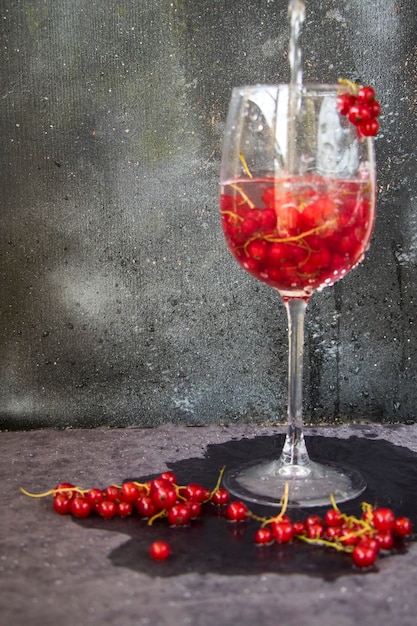 Red currant in the wineglass on the gray and blue background. Large group of colorful berries.