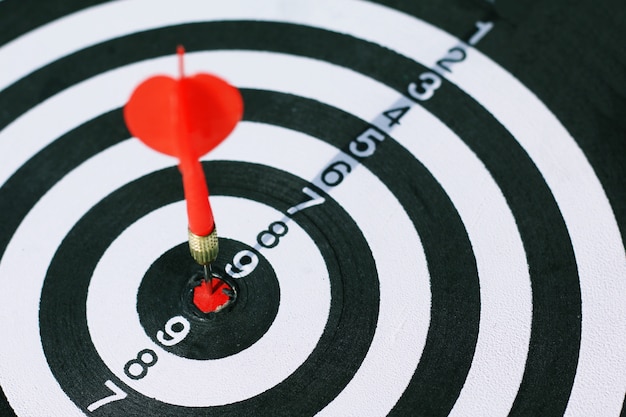 Red dart arrow hit in the target center of dartboard