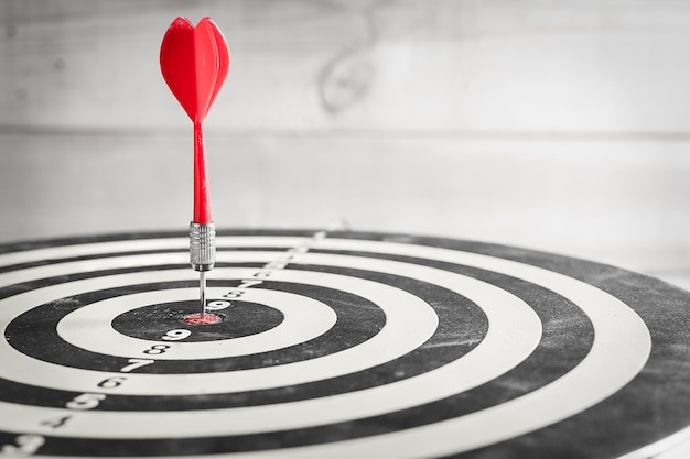 Red dart arrow hitting in the target center of dartboard