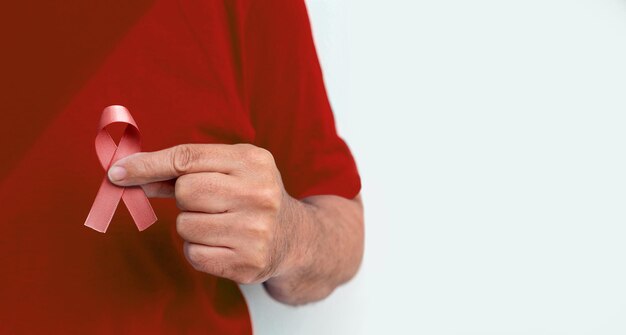 Red december, campaign to fight AIDS. Hand holding red ribbon.