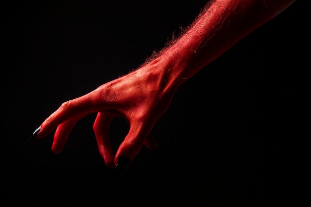 Red devil creepy halloween hand on a black background