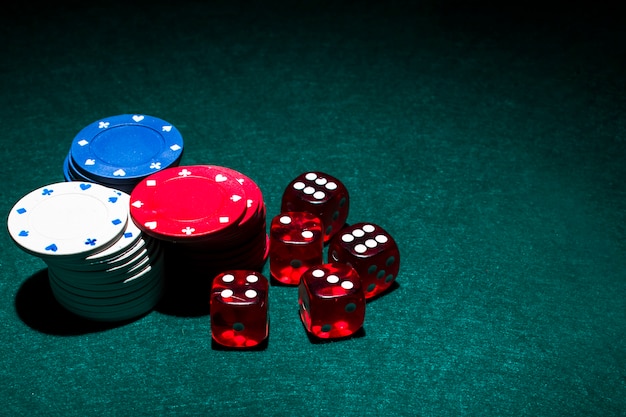 Red dices and casino chips stack on green poker table