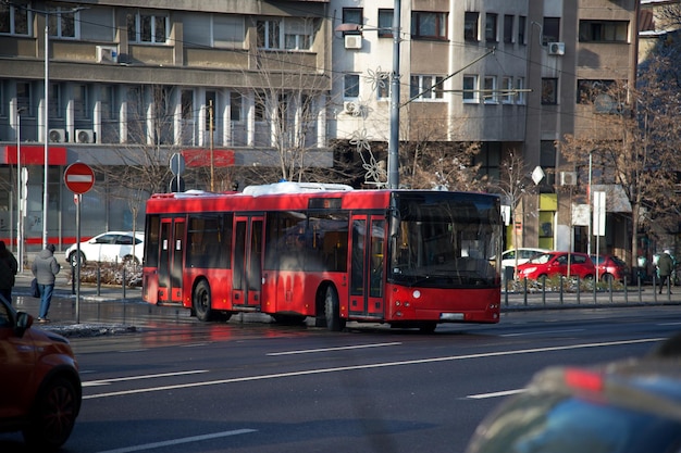 red dirty bus in the middle of the street in the city