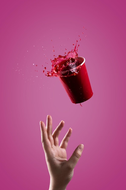 The red drink splashes out of a red paper cup