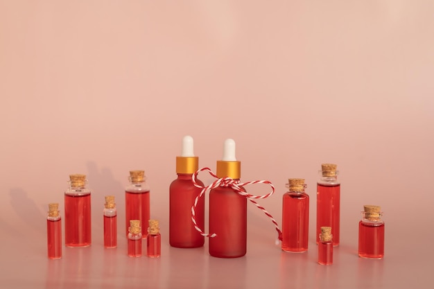 Red dropper bottles of pomegranate serum or oil for face and body standing on a pink background