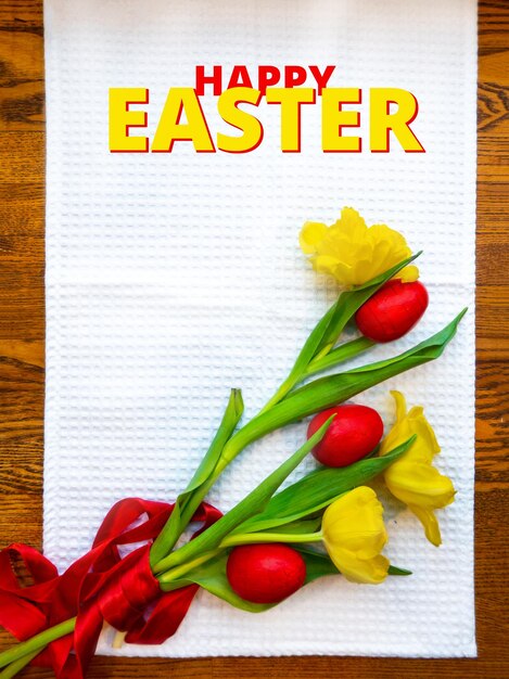 red eggs are lying on the table among yellow tulips tied with a scarlet ribbon A plate with quail eggs caviar nests and a chicken figurine made of yolks is the concept of an Easter dish