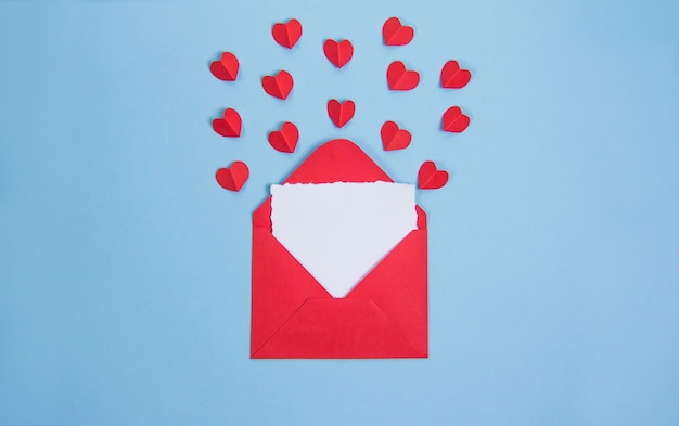 Red envelope with card for text on blue background, red Valentine's day hearts, copy spaÑe