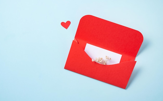 Red envelope with white letter and flowers  on a gray background. The concept of Valentine's Day. Flat lay, copy space and top view.