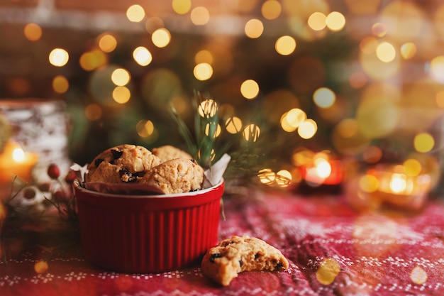 Red festive bowl full with christmas cookies blurred christmas fir tree lights