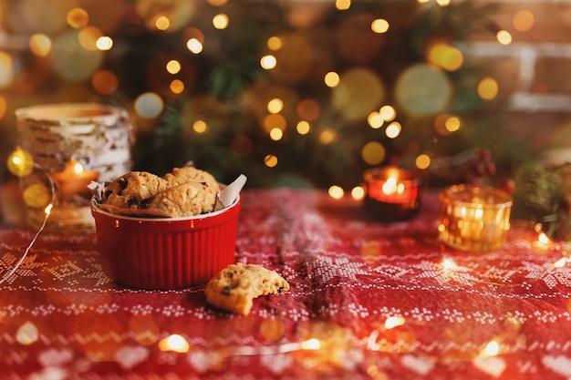 Red festive bowl full with christmas cookies blurred christmas fir tree lights