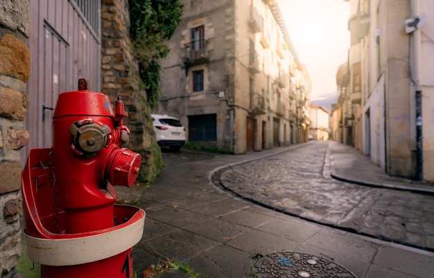 Red fire hydrant on sidewalk in Onati city Spain Fire hydrant on blur old building white car