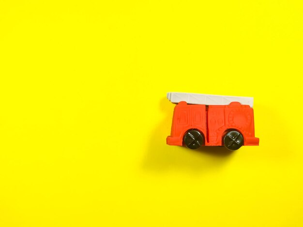 Photo red fire truck toy on a yellow background with copy space