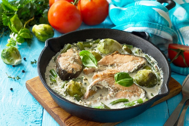 Red fish and vegetables baked brussels sprouts green beans in cream sauce in a frying pan