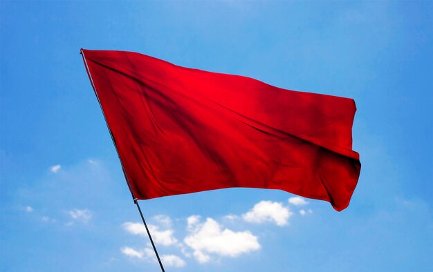 a red flag is flying in the sky with clouds in the background