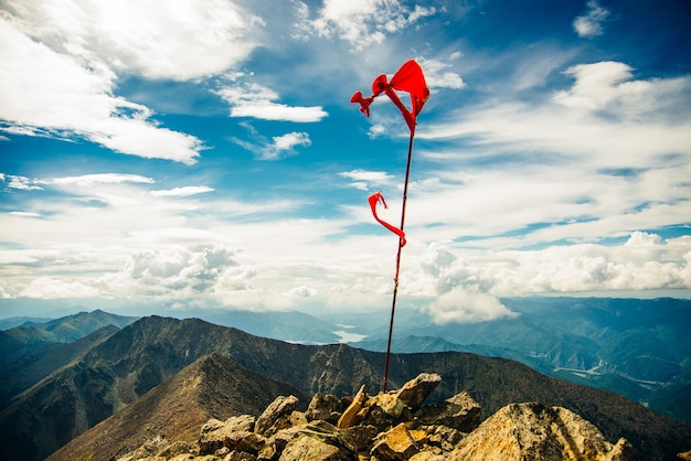 Red flag on top of the mountain with blue sky