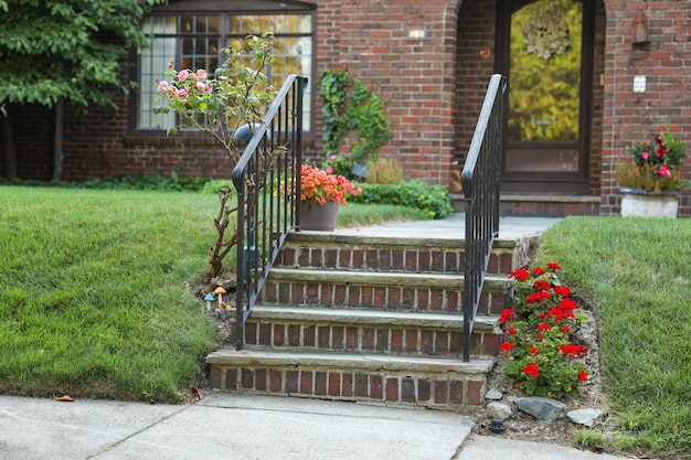 A red flower pot sits on the steps of a house.