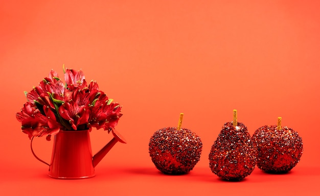 Red flowers in a watering can with red decorative apples on red. St. Valentine's Day