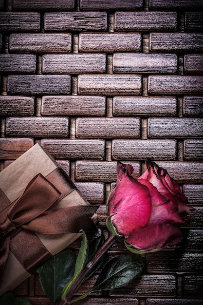 Red fragrant rose wrapped giftbox on wicker wooden matting