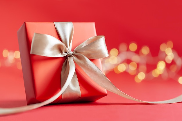 Red gift box with bow on red background Happy Birthday or Valentine's Day concept