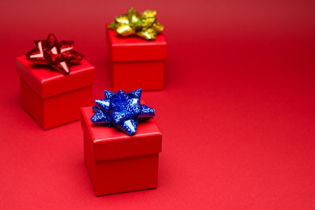 Red gift box with colored ribbon on red background