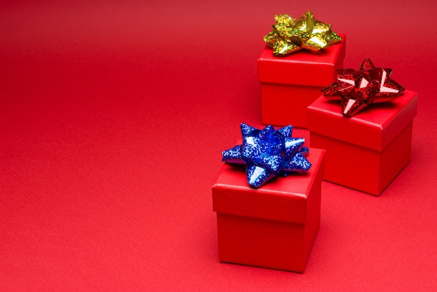 Red gift box with colored ribbon on red background