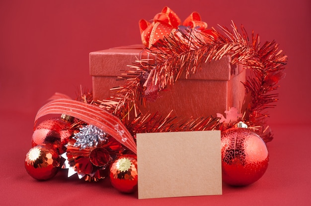 Red Gift Box with Decorations and Card on Red background. Christmas Holiday Concept